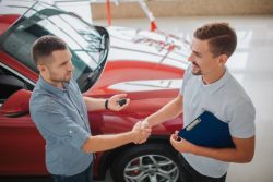 serious-men-stand-shake-each-other-s-hands-purchaser-holds-car-key-dealler-hold-tablet-they-made-deal-red-car-belongs-men-left_152404-5646